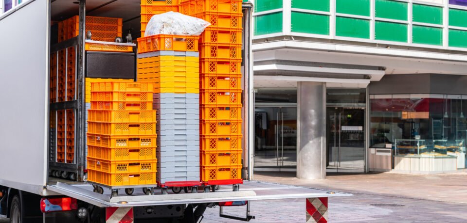 A car with plastic orange and white boxes for goods stands on the pedestrian zone of the city.