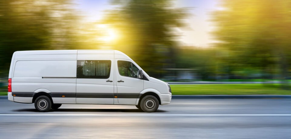 White van moving on a city road at sunset landscape background. Small truck delivers the goods